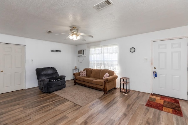 living room featuring visible vents, ceiling fan, a textured ceiling, and wood finished floors