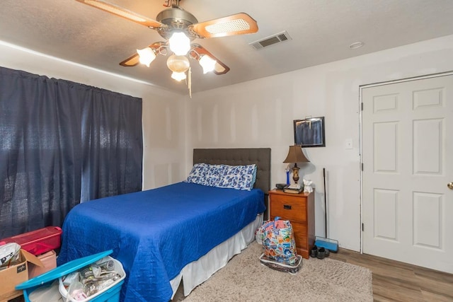 bedroom featuring ceiling fan, wood finished floors, and visible vents