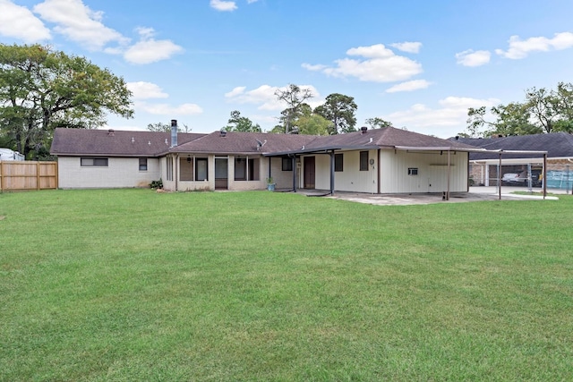 back of property with fence, a lawn, and a patio