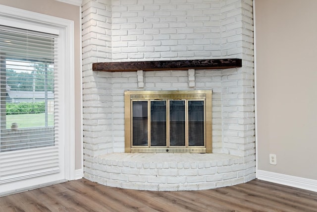 interior details with a fireplace, baseboards, and wood finished floors