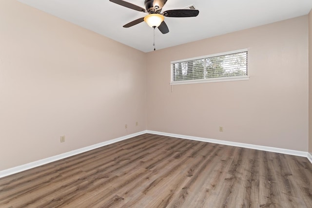 spare room with wood finished floors, a ceiling fan, and baseboards