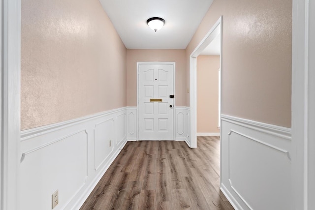 doorway to outside with a wainscoted wall and wood finished floors