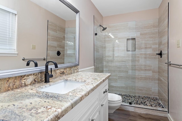 full bath featuring a stall shower, vanity, toilet, and wood finished floors