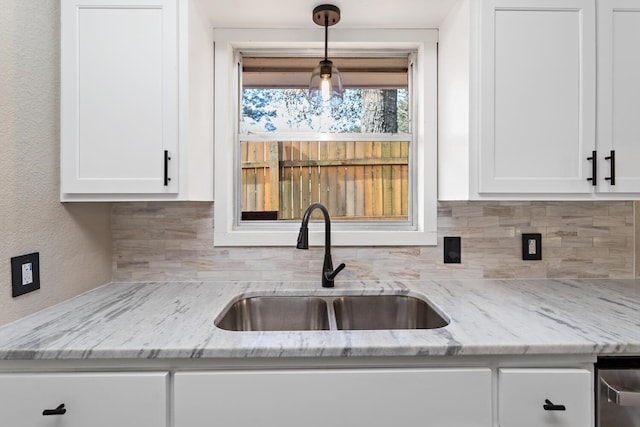 kitchen featuring sink, backsplash, white cabinets, and light stone counters