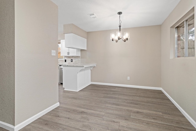 unfurnished dining area featuring a notable chandelier and light hardwood / wood-style floors