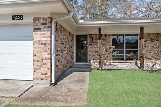 view of exterior entry with a garage and a yard