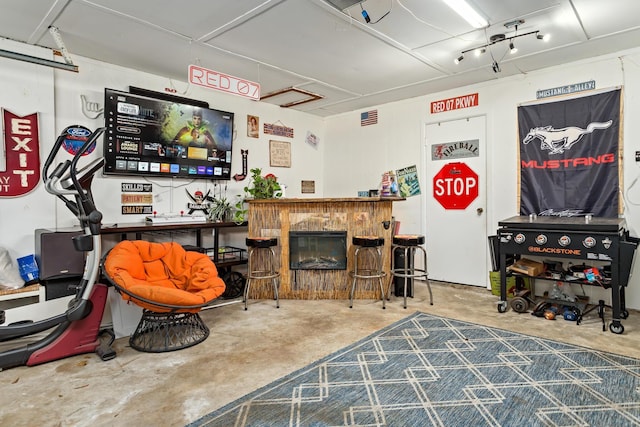 rec room featuring a fireplace and unfinished concrete floors