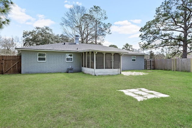 back of property with brick siding, a lawn, a chimney, and a fenced backyard