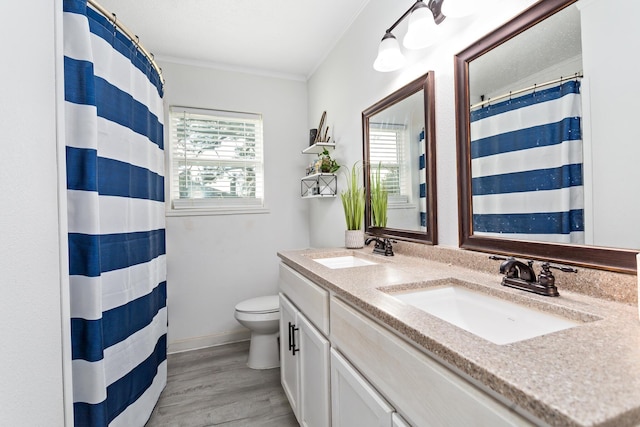 full bathroom with double vanity, a sink, toilet, and wood finished floors