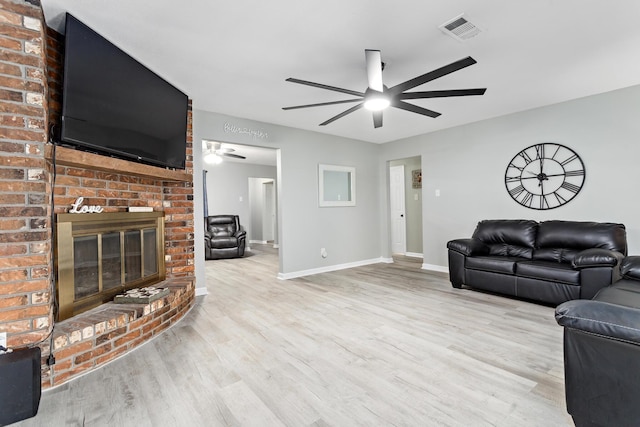 living area with visible vents, a brick fireplace, ceiling fan, wood finished floors, and baseboards