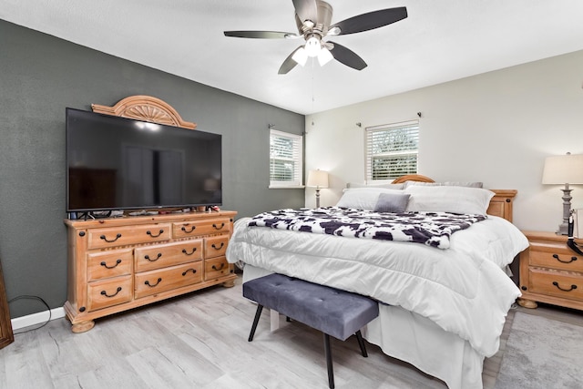 bedroom with light wood finished floors, a ceiling fan, and baseboards