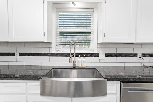 kitchen with white cabinets, a sink, backsplash, and stainless steel dishwasher