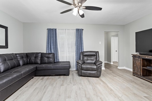 living room featuring baseboards, a ceiling fan, and wood finished floors