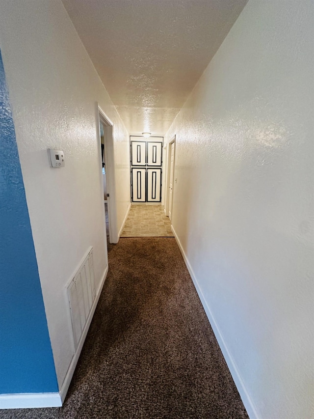 corridor featuring carpet and a textured ceiling