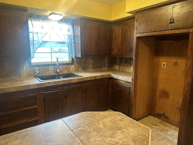 kitchen with dark brown cabinets, sink, and tasteful backsplash