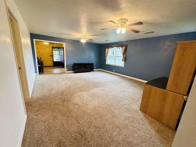 unfurnished living room with ceiling fan, carpet floors, and a textured ceiling