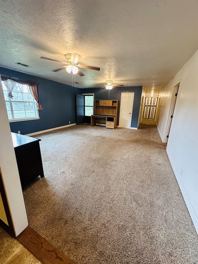 unfurnished living room featuring carpet, plenty of natural light, ceiling fan, and a textured ceiling