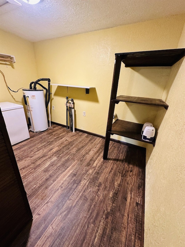 exercise room with wood-type flooring, a textured ceiling, washer / clothes dryer, and water heater