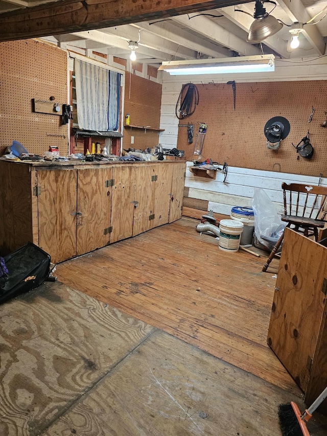 misc room featuring wood-type flooring, a workshop area, and wooden walls