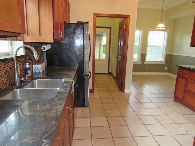 620 20th St, Beaumont, TX 77706 - kitchen featuring backsplash, ornamental molding, light tile patterned floors, hanging light fixtures, and brown cabinetry