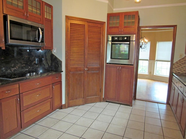 620 20th St, Beaumont, TX 77706 - kitchen with stainless steel appliances, backsplash, a chandelier, ornamental molding, and glass insert cabinets