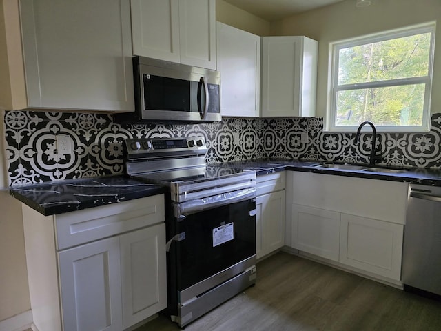 3435 Kenwood Dr, Beaumont, TX 77706 - kitchen featuring a sink, white cabinetry, tasteful backsplash, stainless steel appliances, and dark countertops