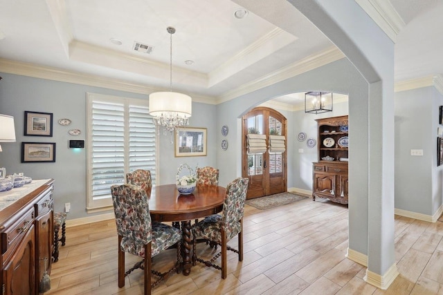 dining area with arched walkways, visible vents, a notable chandelier, and a tray ceiling