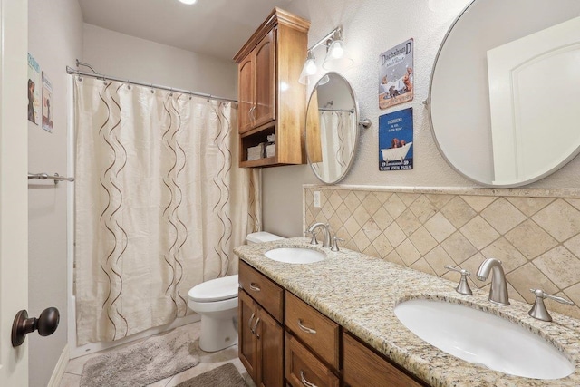 bathroom featuring toilet, double vanity, backsplash, and a sink