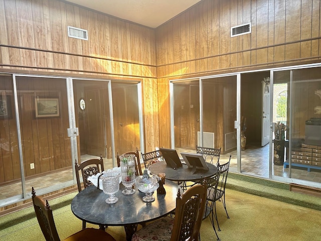 dining room with wood walls and carpet floors