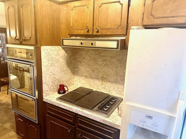 kitchen with black oven, decorative backsplash, stovetop, and white fridge