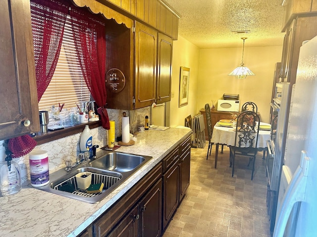 kitchen with a textured ceiling, sink, and hanging light fixtures