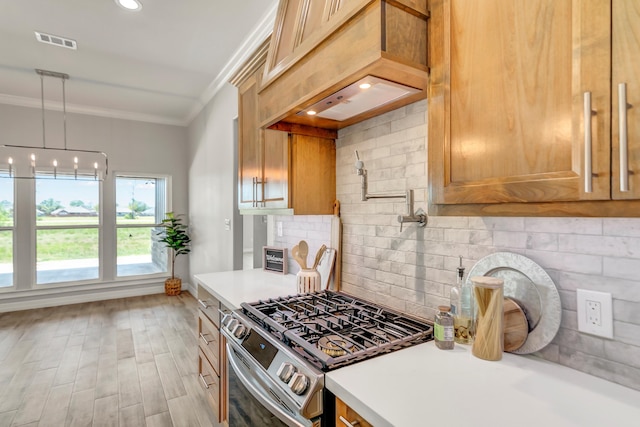 kitchen featuring gas range, light hardwood / wood-style floors, decorative backsplash, custom range hood, and ornamental molding