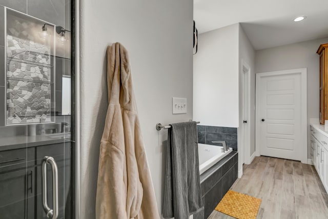 bathroom featuring shower with separate bathtub, vanity, and wood-type flooring