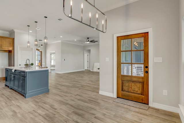 kitchen with pendant lighting, blue cabinets, sink, ceiling fan, and ornamental molding