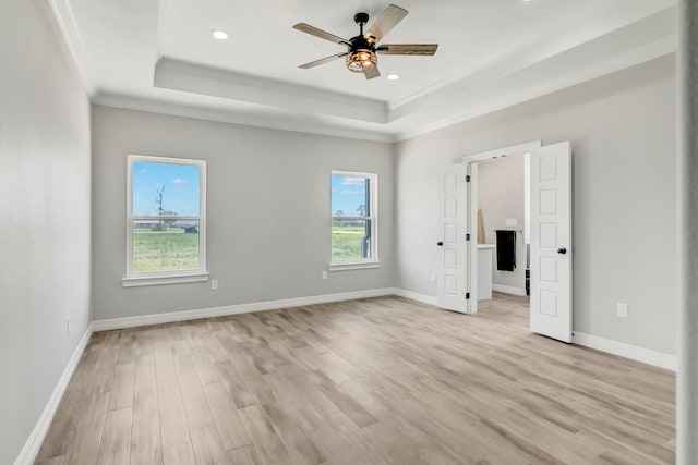 unfurnished bedroom with multiple windows, a raised ceiling, and ceiling fan