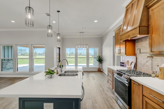 kitchen with gas stove, sink, an island with sink, and hanging light fixtures