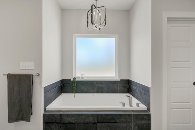 bathroom featuring tiled tub and a chandelier