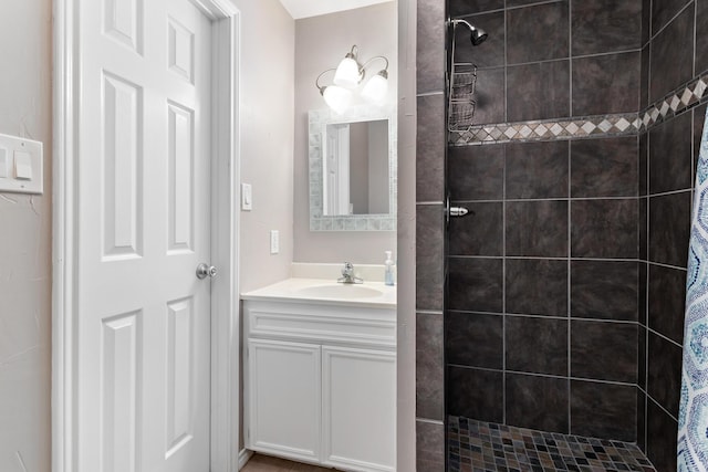 bathroom with a tile shower and vanity