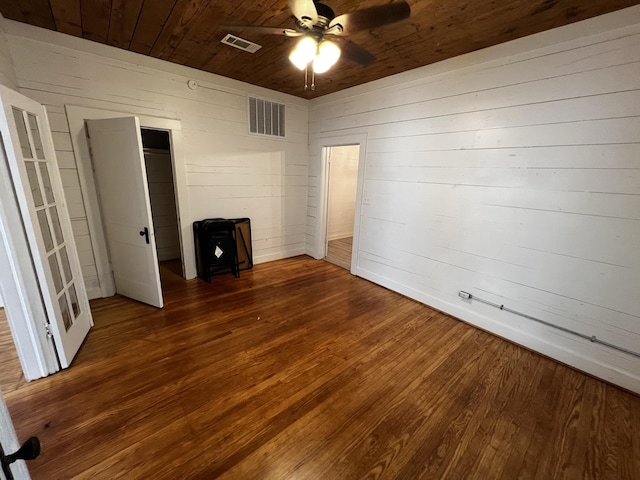 unfurnished bedroom featuring dark wood-type flooring, ceiling fan, wood walls, and wood ceiling