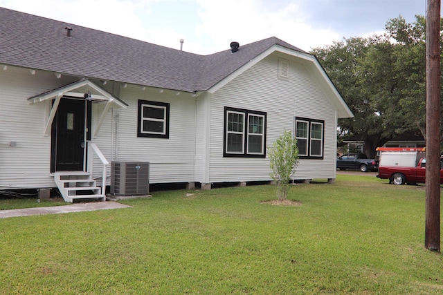 rear view of property featuring cooling unit and a lawn