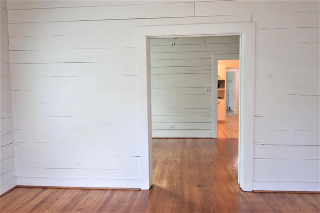 corridor with dark hardwood / wood-style floors and wooden walls