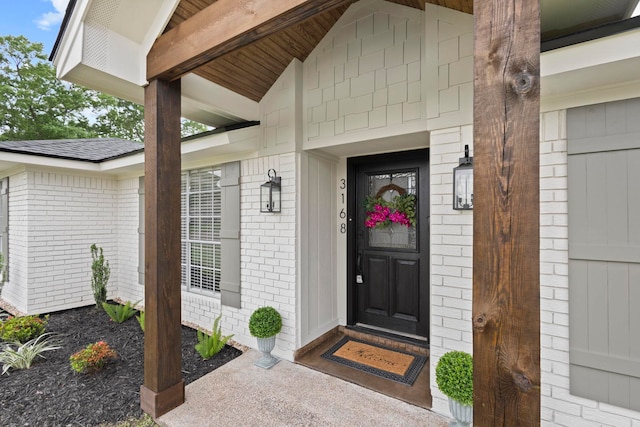 view of exterior entry featuring brick siding