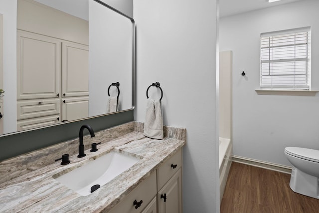 bathroom featuring baseboards, wood finished floors, toilet, and vanity