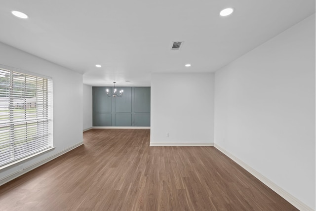 unfurnished room featuring wood finished floors, an inviting chandelier, baseboards, visible vents, and recessed lighting