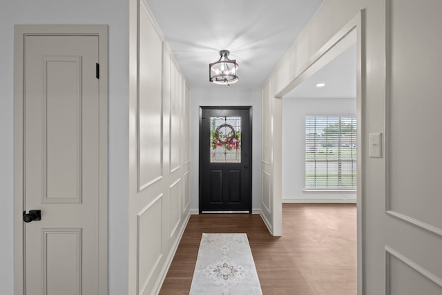 foyer entrance featuring dark wood finished floors, baseboards, and a notable chandelier