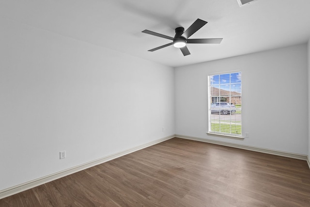 spare room with wood finished floors, a ceiling fan, and baseboards