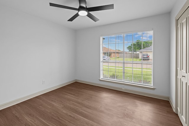 spare room featuring wood finished floors, baseboards, and ceiling fan