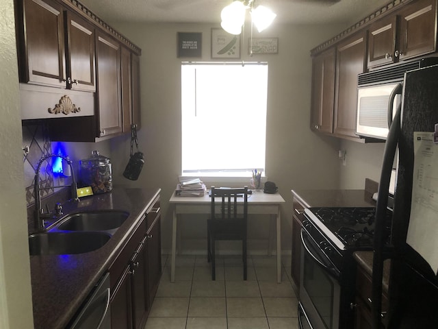 kitchen featuring light tile patterned flooring, freestanding refrigerator, a sink, gas range oven, and stainless steel dishwasher