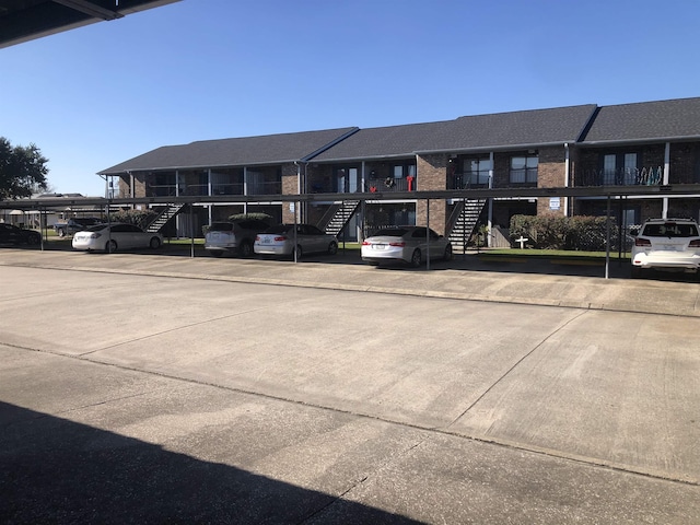 view of building exterior with a residential view, covered parking, and stairs