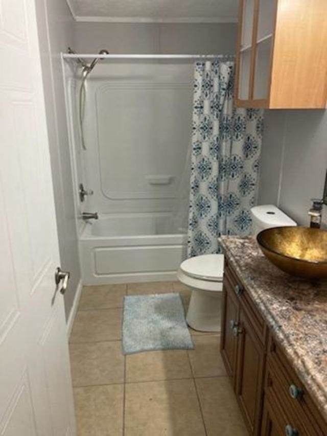 full bathroom featuring tile patterned floors, vanity, toilet, ornamental molding, and shower / bath combo with shower curtain